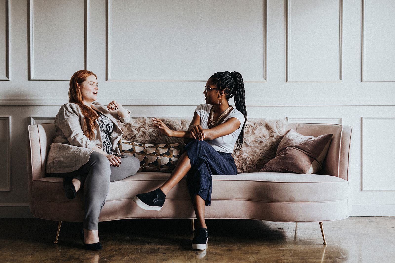 two women sitting on a sofa talking to each other