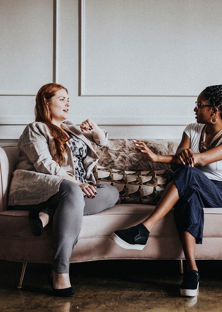 two women sitting on a sofa talking to each other